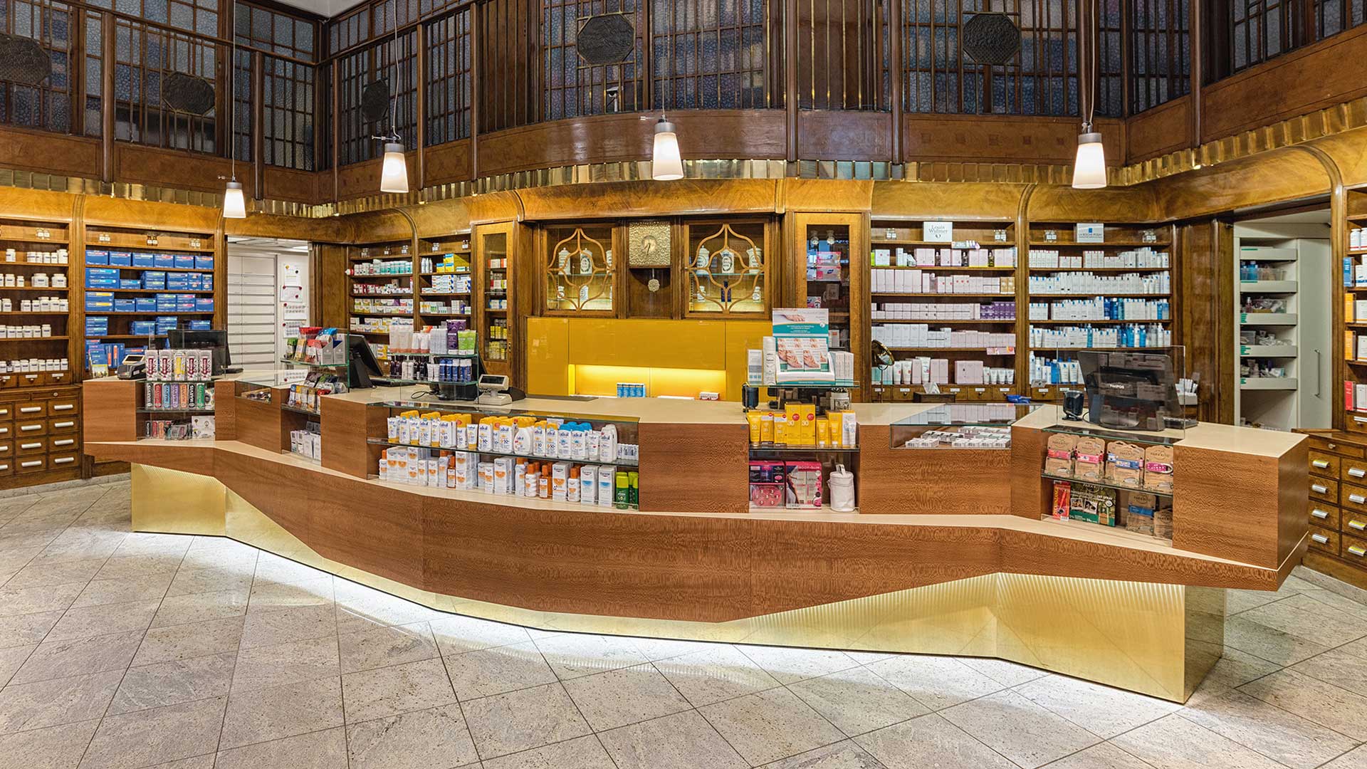 Beleuchteter Empfang mit Tresen und Medikamentenregalen und Apothekenkosmetik in Wien